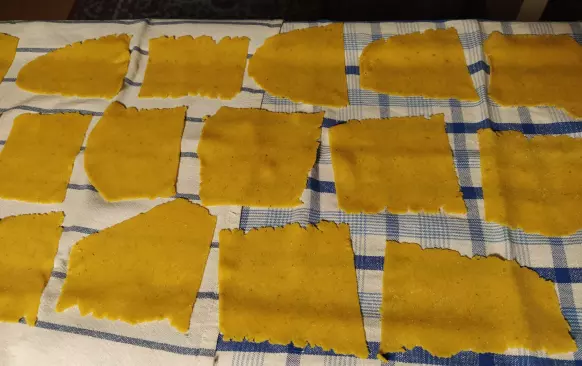 Těsto krátce prohněteme a vyválíme. Utvoříme čtverečky nebo obdélníčky. Na tvaru až tak nezáleží. Krásně se to válí bez lepení na silikonové podložce a přes fólii. 
Pokud máte strojek na těstoviny, protáhneme strojkem na č. 5. Nižší stupeň nedoporučuji, pak je těsto příliš tenké a může se trhat.
Jak vidno, kousky těstovin nejsou přesné čtverečky či obdélníky, vůbec to nevadí.