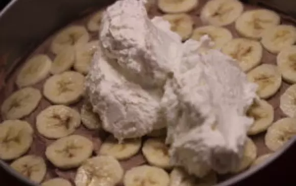 Hotovej korpus necháme schladnout a mezitim si nakrájíme banány na tenký kolečka a ušleháme obě šlehačky do tuha.
Korpus řízneme vejpůl, do spodní strany vetřeme marmeládu, poklademe kolečkama ze dvou banánů, zakryjeme pařížskou šlehačkou, dáme zbylý banán a znovu zakryjeme, tentokrát šlehačkou bílou.