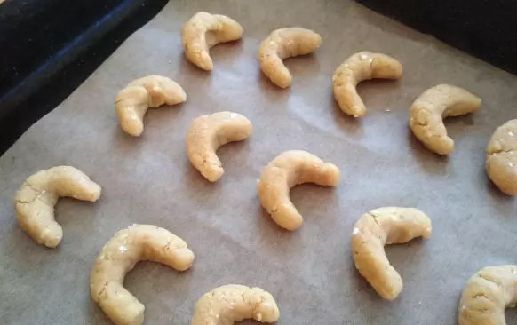 Do moučné směsi nasekejte 35 g másla. Třecím nástavcem v robotu a nebo vidličkou do směsi máslo zapracujte - pracujte rychle, aby se suroviny co nejméně zahřály.
Když je mouka s máslem rozemnutá do jemné drobenky, přidejte žloutky i rum a opět zapracujte.
Těsto rychle vyválejte do válečku a rozdělte na 15 stejných dílků. Z nich rychle vytvarujte rohlíčky.