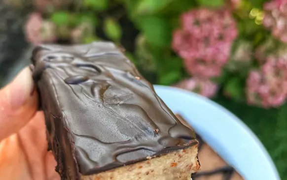 1. Nejdříve si připravíme první vrstvu. Mandle, kokosovou mouku a banán na první vrstvu rozmixujeme. Přimícháme kokosový olej. Vznikne nám těsto, které rozprostřeme do formy (velikost 22x9 cm) s pečicím papírem. Posypeme nasekanými oříšky, které do těsta lehce zatlačíme a dáme do mrazáku.

2. Mezitím si připravíme další vrstvu. Všechny ingredience na druhou vrstvu rozmixujeme, nalijeme na první vrstvu a dáme na 4 hodiny do mrazáku. Poté těsto rozřízneme na tyčinky, rozehřejeme hořkou čokoládu (asi 30-50 g) ve vodní lázni a obalíme tyčinky. Skladujeme v lednici.