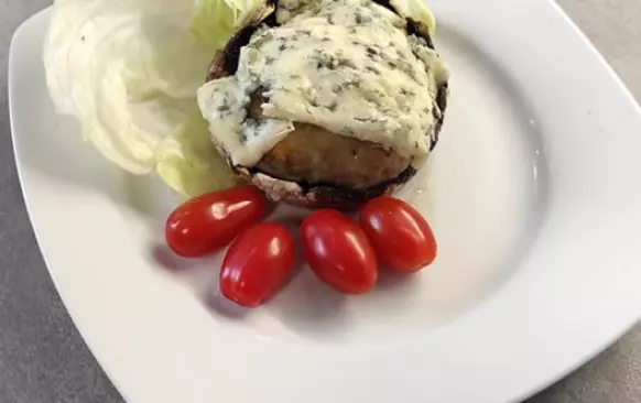 Nejdříve ulomte žampionům nožičky. Dejte na pánvičku rozehřát máslo, nakrájejte nožičky a cibulku. Orestujte to na rozehřátém másle. 
Do misky dejte kuřecí mleté maso, přidejte orestovanou cibulku a nožky ze žampionů., česnek, vejce a nastrouhaný sýr. Důkladně vše promícháme. Do pekáčku na pečící papír uděláme deset kusů karbanátků. Pečeme je při 150 stupních dvacet minut. 
Připravíme si další pekáček, kam připravíme  portobella. 
Upečené karbanátky položíme na portobella. Vršek pokryjeme tenoučkými plátky nivy. Dáme zapéct na deset minut na 150 stupňů. Zapečené portobello jsem servírovala se salátem z ledového salátu, chcerry rajčat a okurky. Salát  dochutila jsem balsamikovým