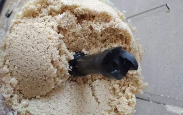 Smíchejte ve food procesoru všechny suché suroviny.  Přidejte máslo. Promixujte do hladké drobenky. Pokud nemáte food procesor, můžete tuk do těsta zamačkat vidličkou, až se rozdrobí. Nedělejte to rukama, těsto se spaří a není to ono. Snažte se pracovat co nejrychleji, aby se suroviny zbytečně nezahřály.
Pak přidejte žloutky a opět zapracujte. Těsto nechte odpočinout v lednici.