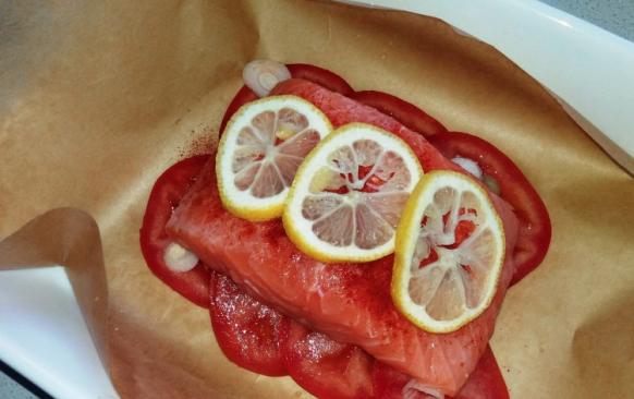 Lososa omyjte a osušte. Na pečicí papír vyskládejte na kolečka nakrájené rajče a posypte kolečky jarní cibulky.
Lososa osolte a opaprikujte z obou stran. Položte na rajčata a pokapte citronovou šťávou. Na povrch položte několik koleček citronu.